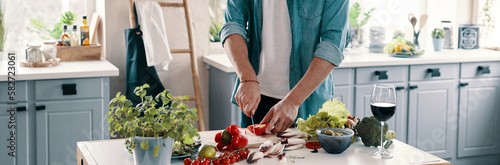 Close-up of unrecognizable man cutting vegetables while standing at the kitchen counter