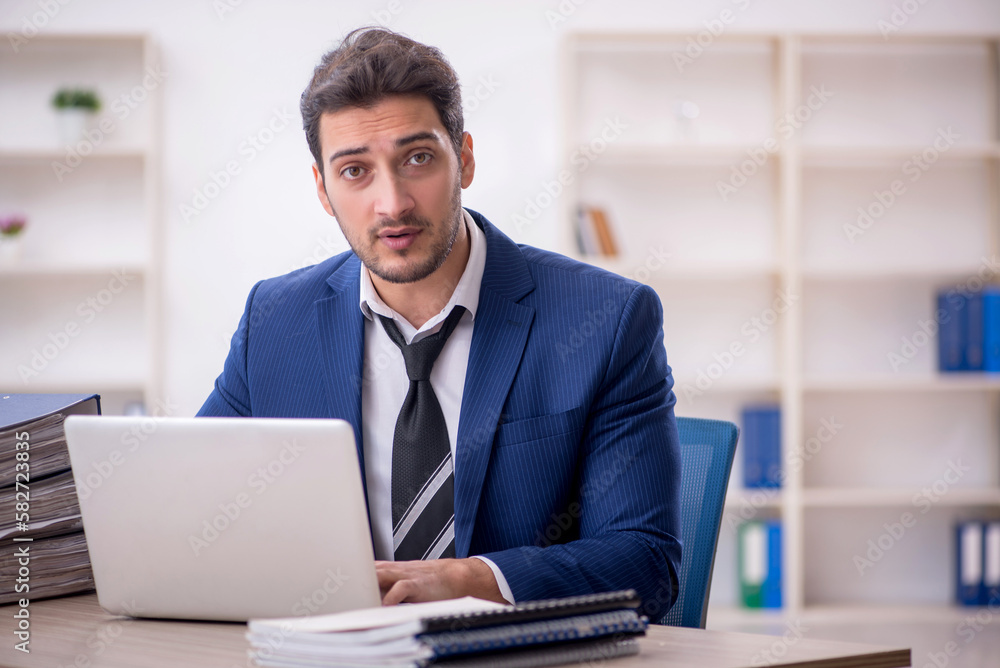 Young male employee and too much work in the office Young male employee and too much work in the office
