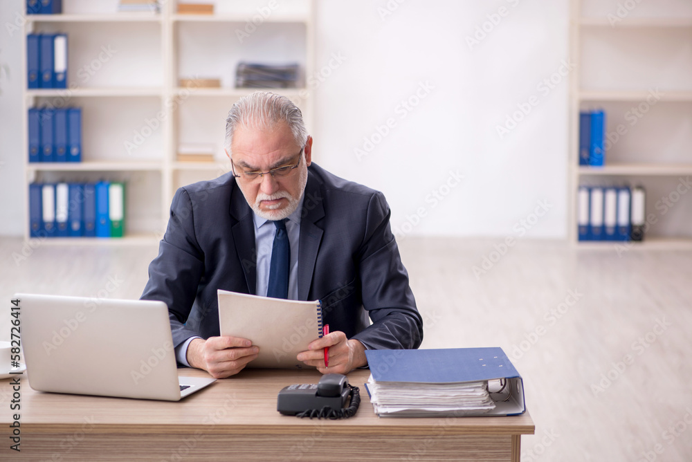 Old male employee working in the office Old male employee working in the office