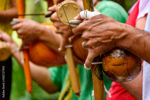 Hands of a musician playing an Afro Brazilian percussion musical instrument called a berimbau during a capoeira performance in the streets of Brazil