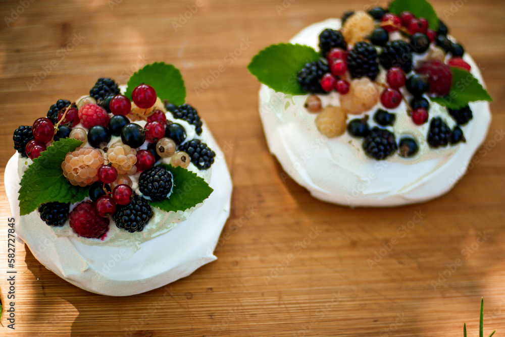 pavlova cakes with summer berries and fruits on a wooden board pavlova cakes with summer berries and fruits on a wooden board