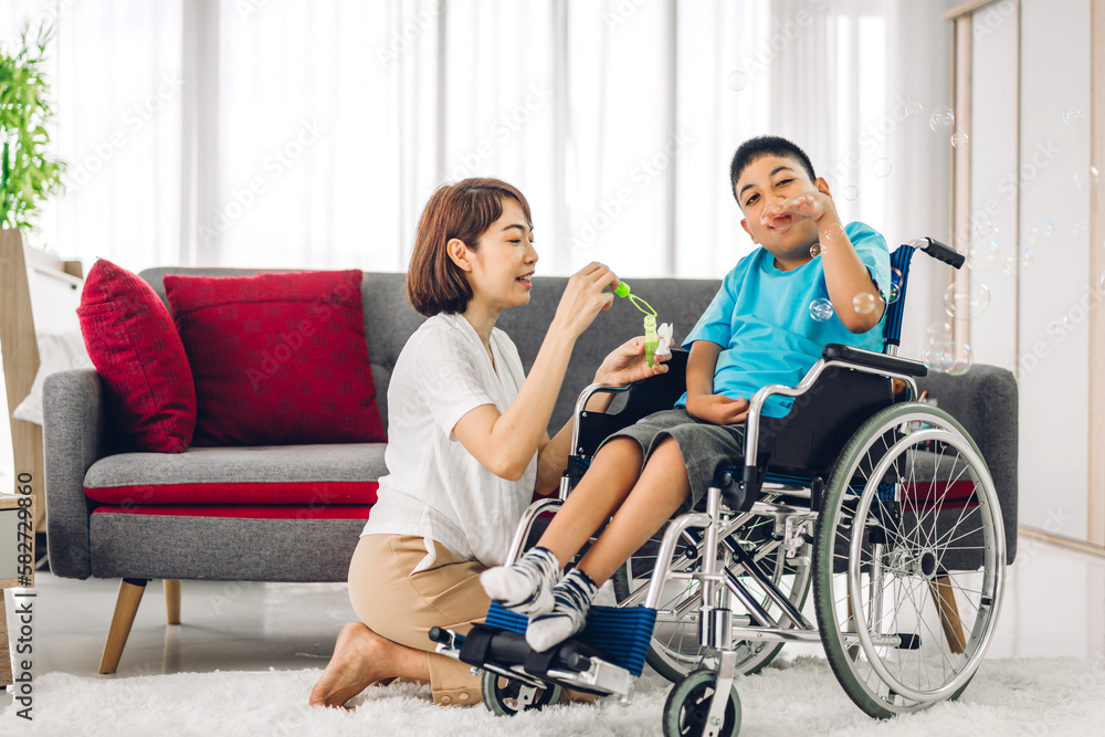 Portrait of enjoy happy love family asian mother playing and carer helping look at disabled son child sitting in wheelchair moments good time at home.disability care concept. Portrait of enjoy happy love family asian mother playing and carer helping look at disabled son child sitting in wheelchair moments good time at home.disability care concept.