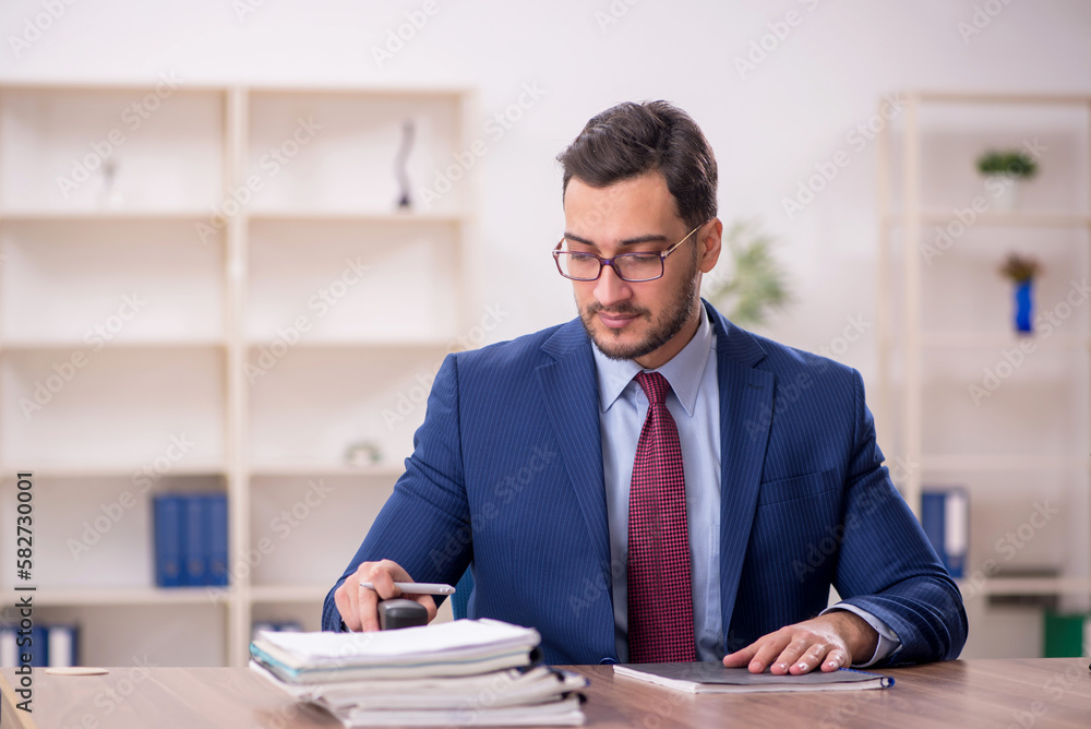 Young male employee and too much work in the office Young male employee and too much work in the office
