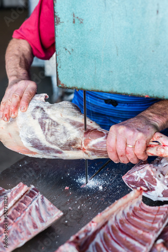 mobile butcher using electric saw to cut the shank from the leg photo