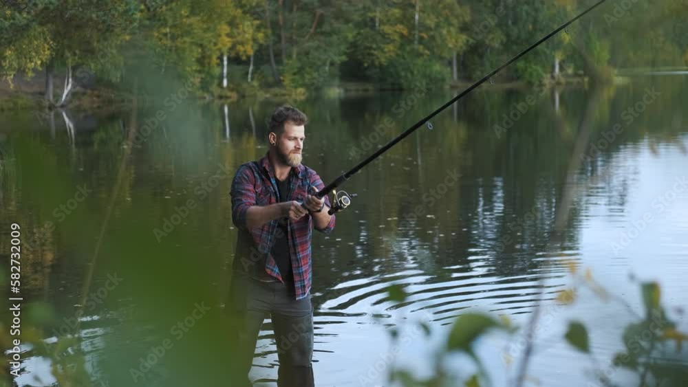 through the grass, a man fishes standing in the water through the grass, a man fishes standing in the water