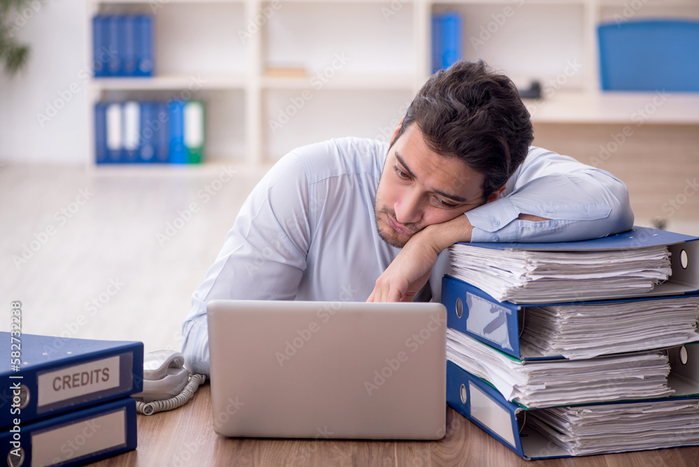 Young male employee and too much work in the office Young male employee and too much work in the office