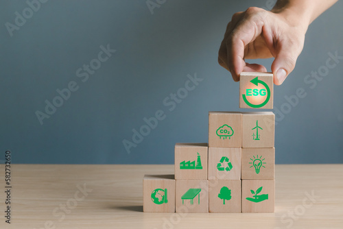 Concept. Environmental Social and Governance (ESG), male hand holding wooden block with ESG text. Show investing in companies use renewable resources that are environmentally friendly