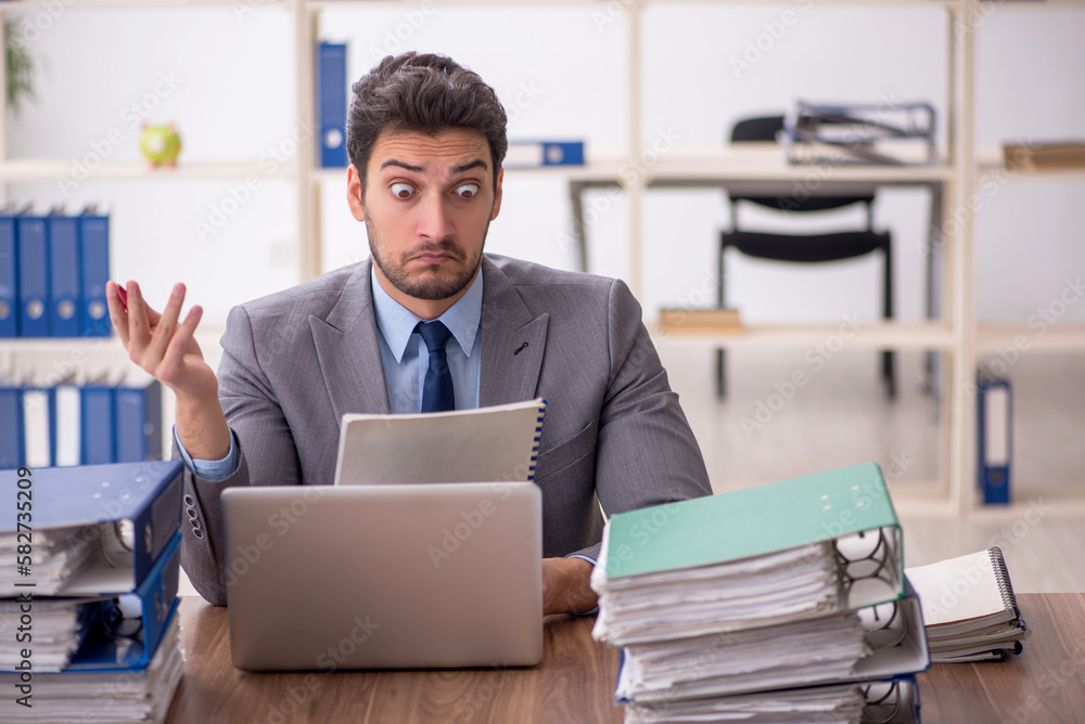 Young male employee and too much work in the office Young male employee and too much work in the office