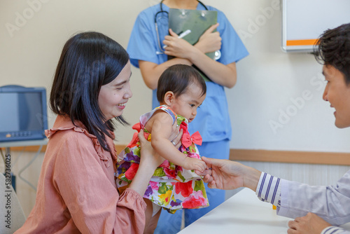 Mother holding cute baby in doctor s office Asian male pediatrician prescribes patient treatment. Medical