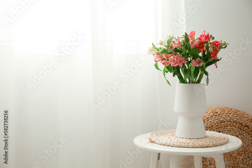 Vase with bouquet of fresh alstroemeria flowers on table in room