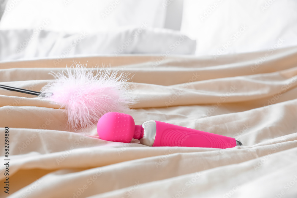 Vibrator and feather stick on blanket in bedroom, closeup Vibrator and feather stick on blanket in bedroom, closeup
