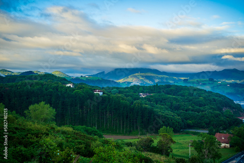 landscape with forest and mountains, in the background mountain peaks in the clouds. Basque Country, Spain.