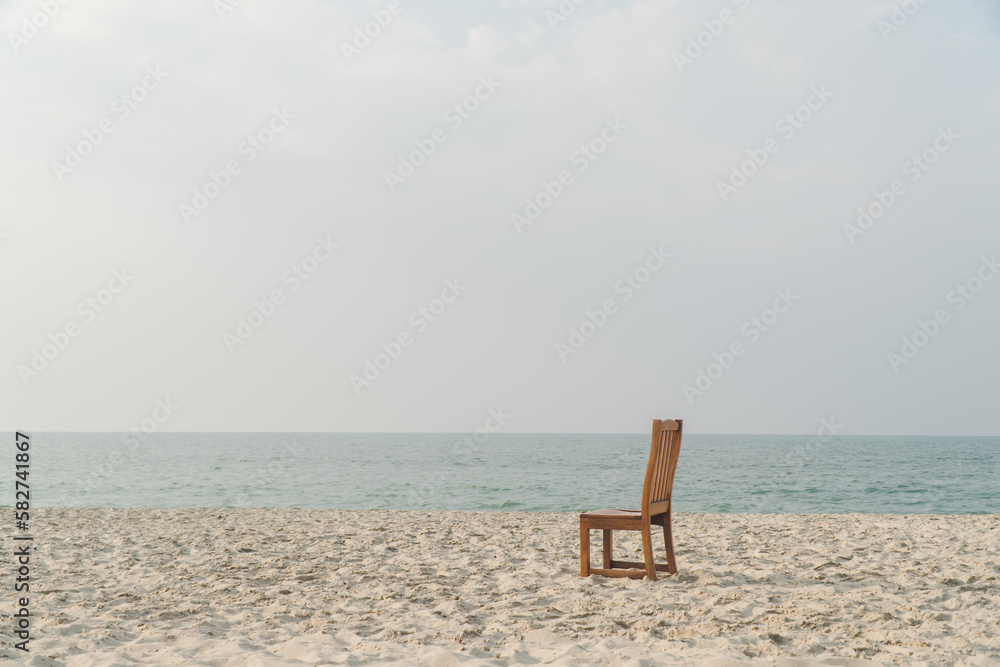 Fototapeta premium A chair with no people on the sea beach in front of a minimalist background. relax on lonely beach. sea sand sky concept. summer vacation. copy space.