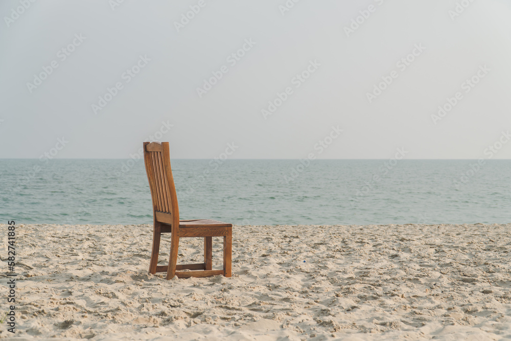 A chair with no people on the sea beach in front of a minimalist background. relax on lonely beach. sea sand sky concept. summer vacation. copy space.