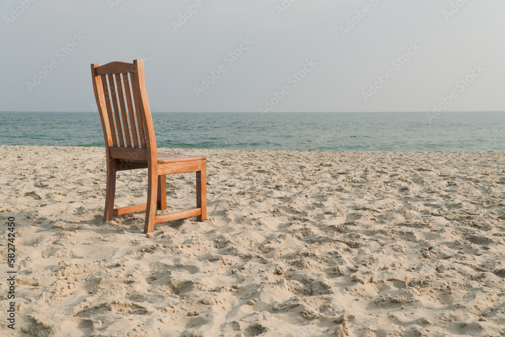 A chair with no people on the sea beach in front of a minimalist background. relax on lonely beach. sea sand sky concept. summer vacation. copy space.