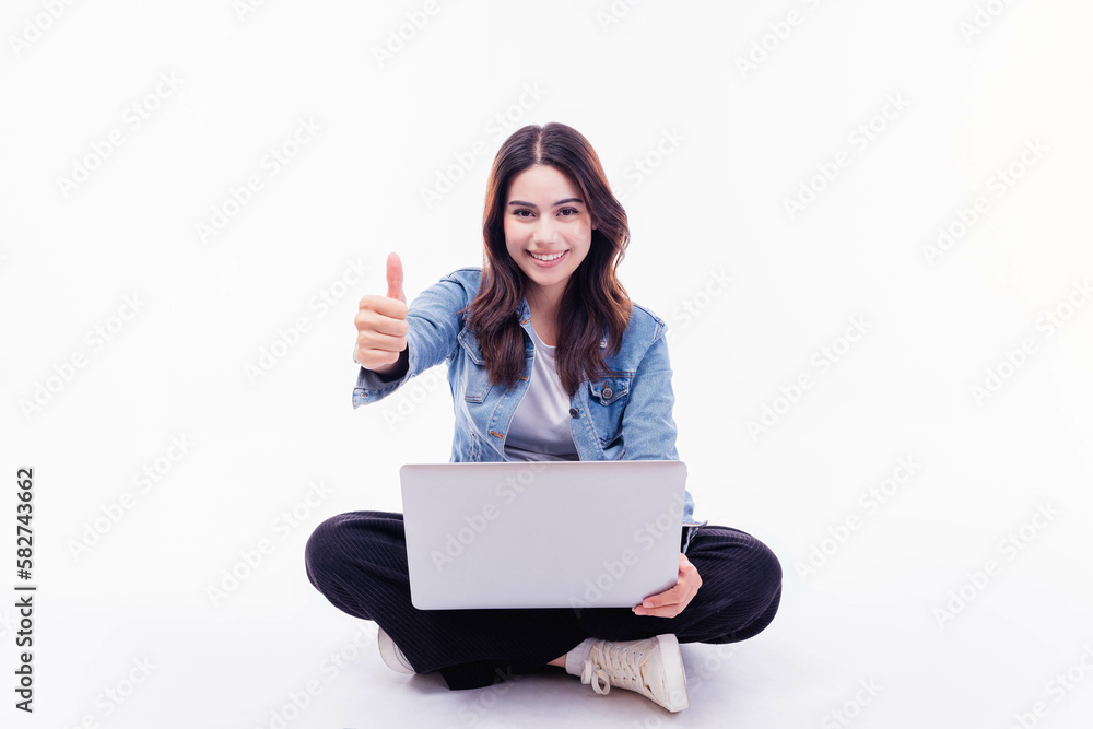 Happy smiling Mixed race young woman working on laptop computer while sitting on floor with thumb up isolated on white background University student girl holding laptop computer with crossed legs Happy smiling Mixed race young woman working on laptop computer while sitting on floor with thumb up isolated on white background University student girl holding laptop computer with crossed legs