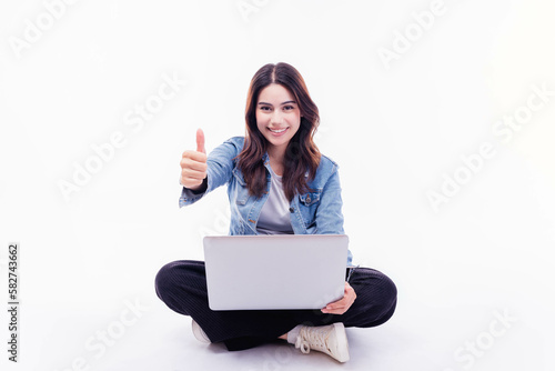 Happy smiling Mixed race young woman working on laptop computer while sitting on floor with thumb up isolated on white background University student girl holding laptop computer with crossed legs