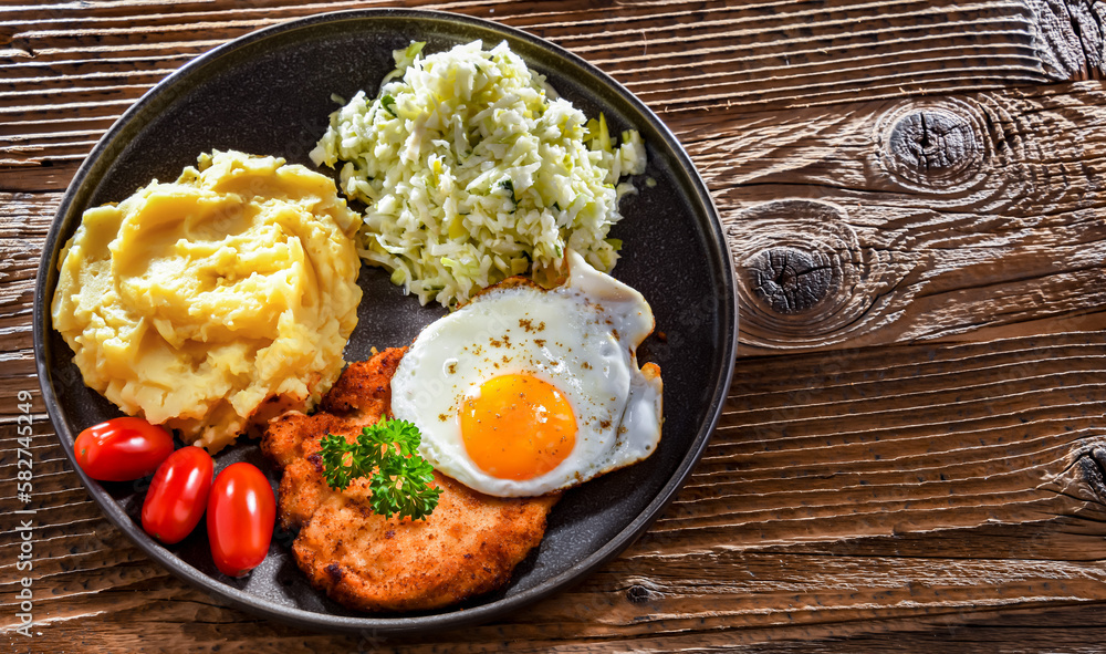 Breaded chicken cutlet with fried egg, potatoes and cabbage Breaded chicken cutlet with fried egg, potatoes and cabbage
