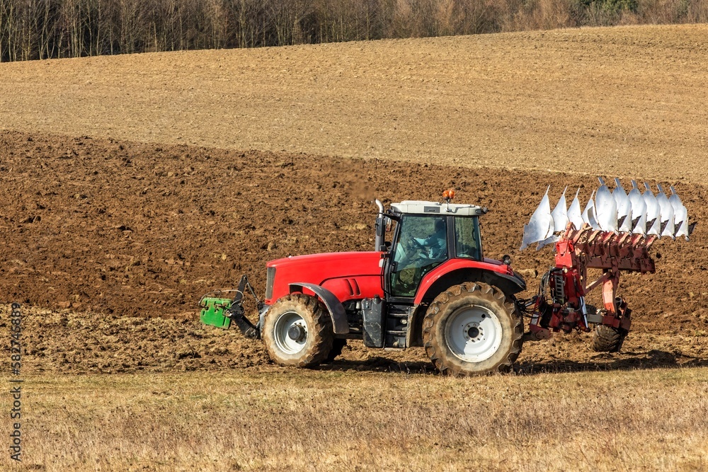 Obraz premium Tractor plowing fields. Spring work on the farm in the Czech Republic. Agricultural landscape. Preparation for sowing grain.