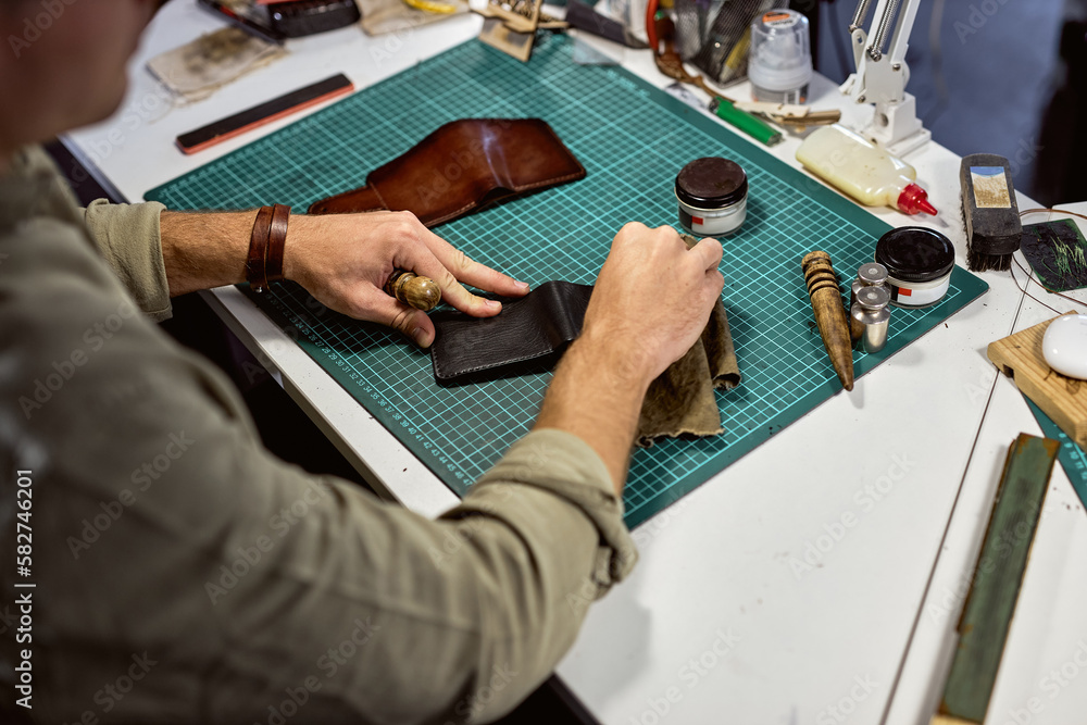 Fototapeta premium professional artisan makes an old leather wallet look new,clean a genuine leather wallet, close up cropped shot. coloring