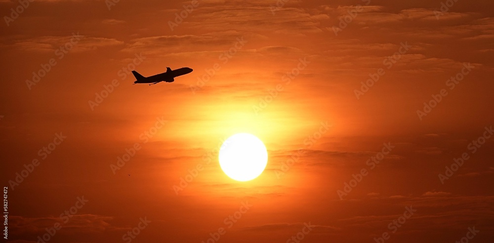 Plane flying against a bright sunset