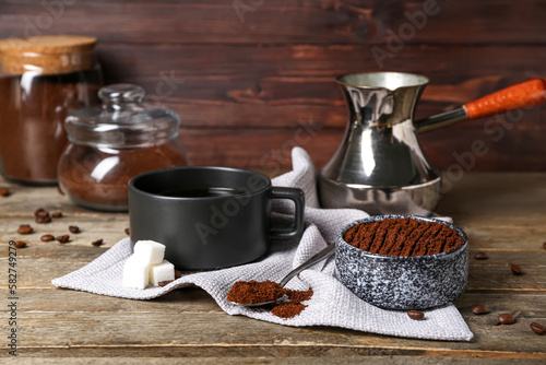 Bowl of coffee powder, sugar and cup on wooden table, closeup