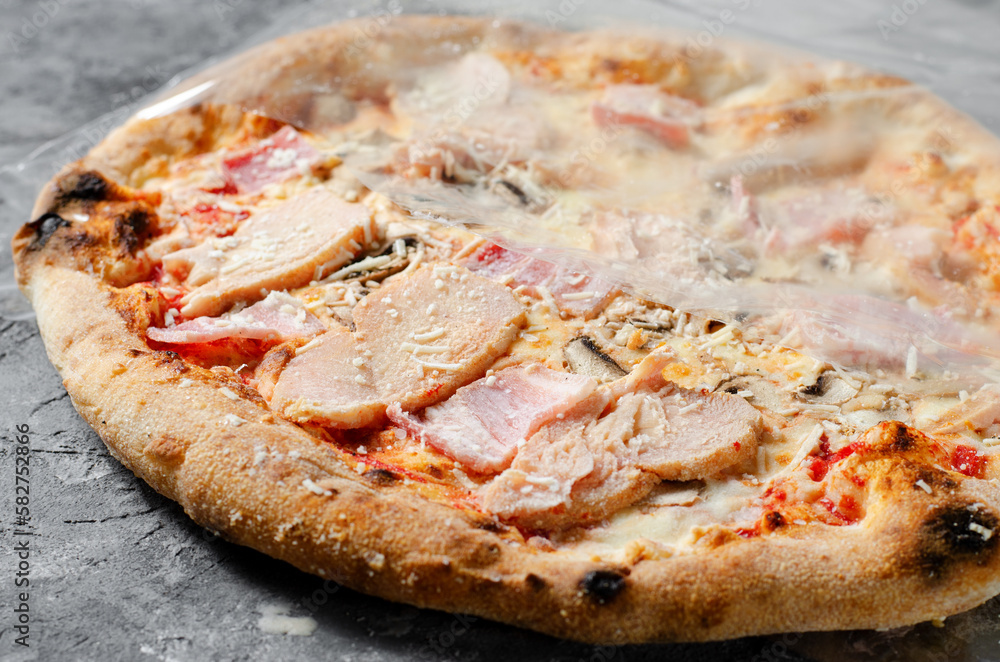 Frozen Chicken, Bacon, Mushroom Pizza on Dark Background, Stone Baked Pizza Ready to Bake Frozen Chicken, Bacon, Mushroom Pizza on Dark Background, Stone Baked Pizza Ready to Bake