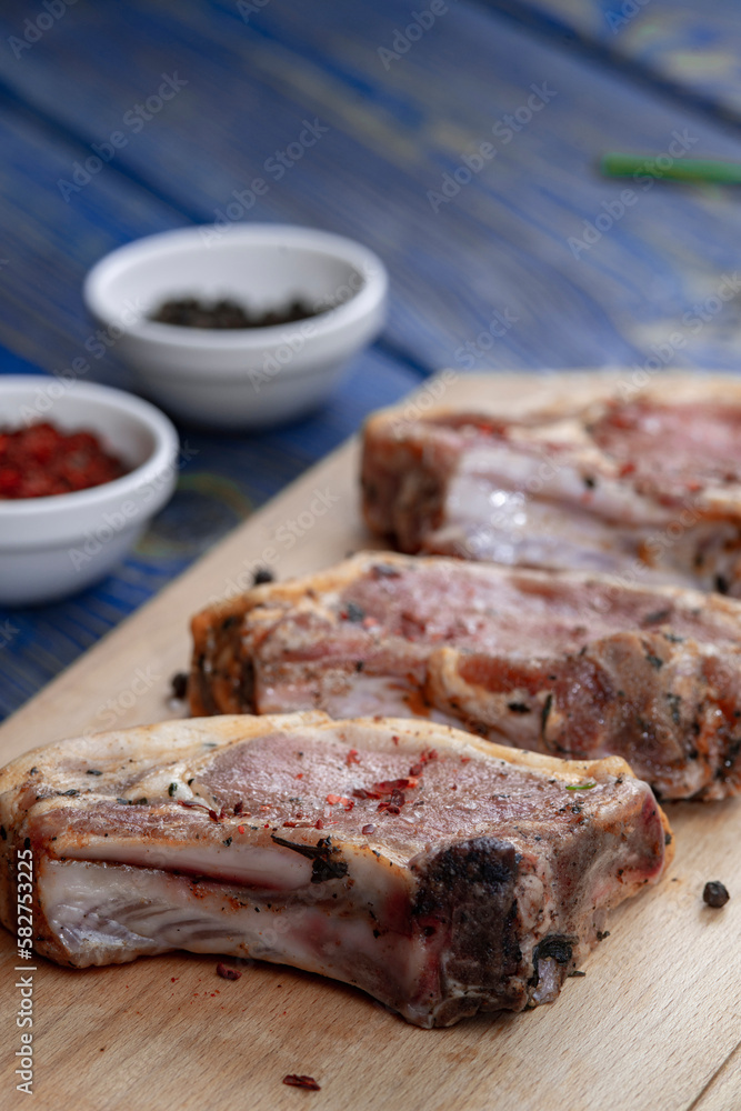 Pieces of raw pork with spices , salt and pepper on blue wooden background in rustic style Pieces of raw pork with spices , salt and pepper on blue wooden background in rustic style