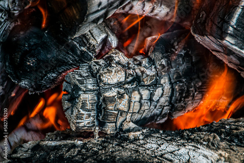 Large burning firewood with ashes in a bonfire closeup