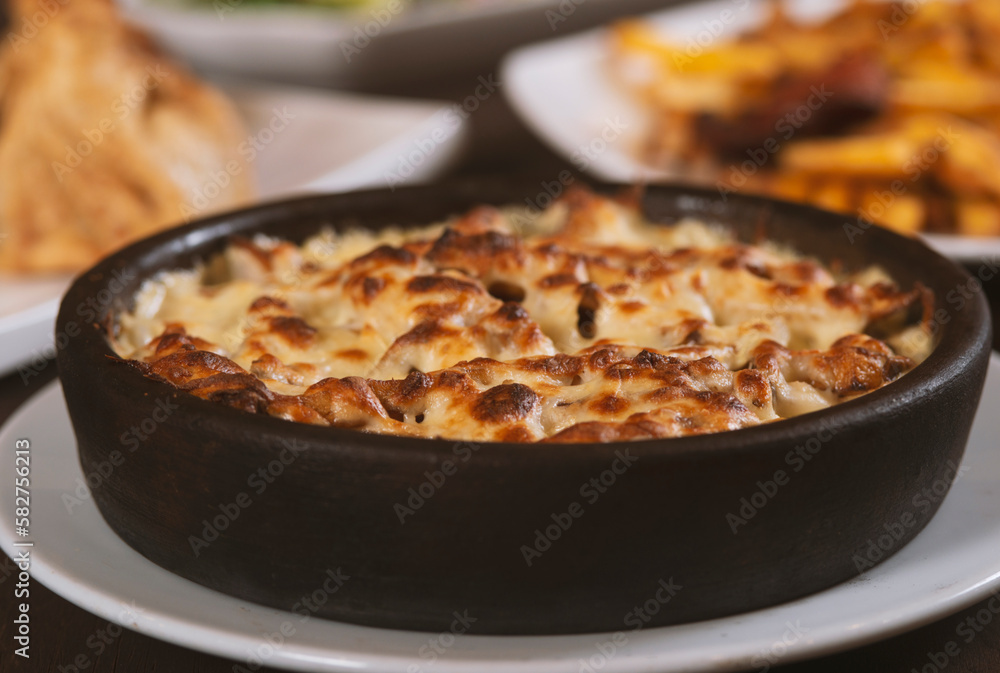 Mushroom and meat casserole covered with melted cheese and served in a dark dish on the table Mushroom and meat casserole covered with melted cheese and served in a dark dish on the table