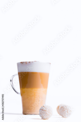 Latte macchiato in a tall glass on a white background. Cafe latte layered with milk in a high drinking glass. Minimalism. Сopy space
