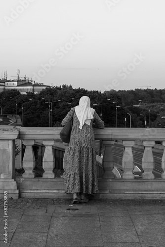 Woman with a white headscarf leaning over the railing © Cezary