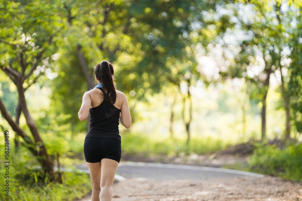 Female jogging in a park in black sportswear surrounded by greenery Female jogging in a park in black sportswear surrounded by greenery