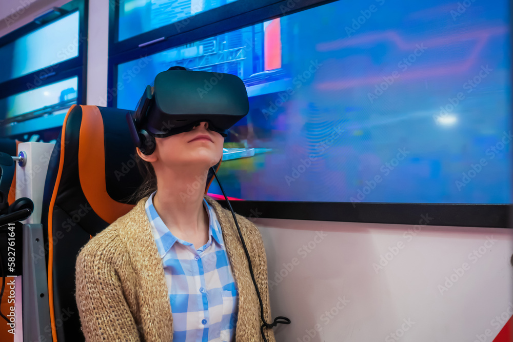 Woman using black virtual reality headset, looking around and playing in passenger of public transport simulator at exhibition. Future and video game concept Woman using black virtual reality headset, looking around and playing in passenger of public transport simulator at exhibition. Future and video game concept
