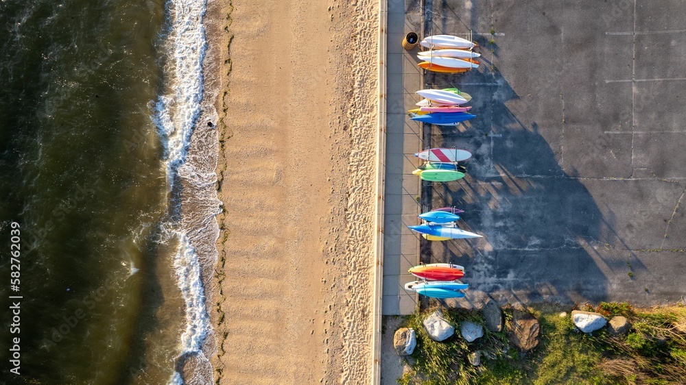 Aerial view of sunrise on gold coast of Long Island, New York, over empty beach with colorful kayaks