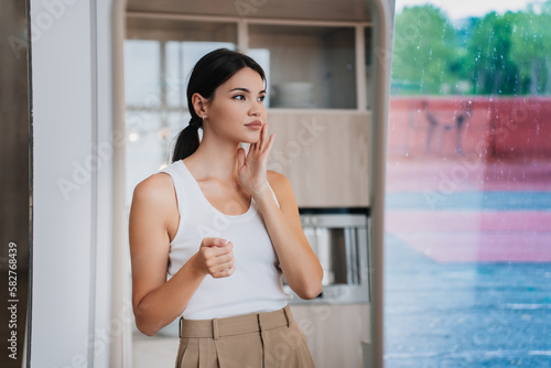 Bored young pretty Asian woman in white t-shirt and beige pants standing at mirror, tired. Attractive Korean girl frustrated after divorce at home. Fashion fit model. Beauty and health care. Free Download Bored young pretty Asian woman in white t-shirt and beige pants standing at mirror, tired. Attractive Korean girl frustrated after divorce at home. Fashion fit model. Beauty and health care. - GFXLoad