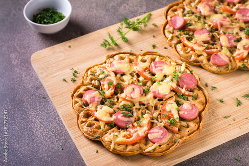 Slika na platnu Appetizing pizza waffle with vegetables, sausages and cheese on a board on the table