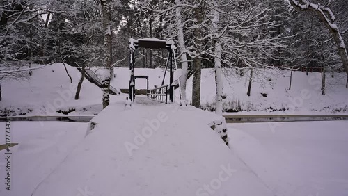Crossing a winter river through a snowy suspension bridge with strong chains.