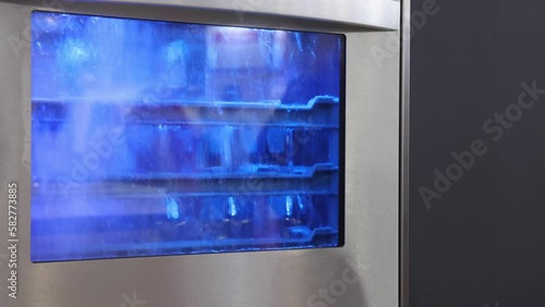 Splashing Water in Commercial Glass Washing Machine With Blue Lights Cleaning Process