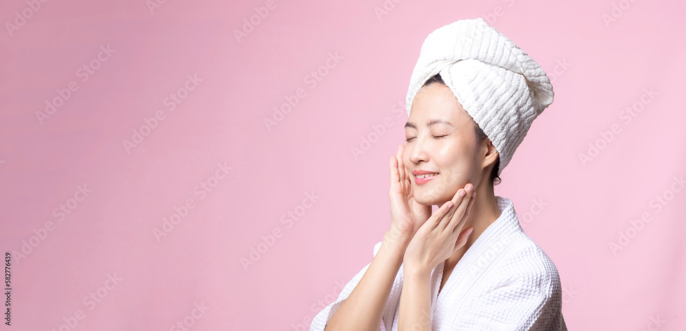 Beautiful young asian woman happy with clean face skin in towel and bathrobe, spa suit on pink background. Skincare, treatment, wellness therapy, facial care, beauty female health, cosmetology concept Beautiful young asian woman happy with clean face skin in towel and bathrobe, spa suit on pink background. Skincare, treatment, wellness therapy, facial care, beauty female health, cosmetology concept