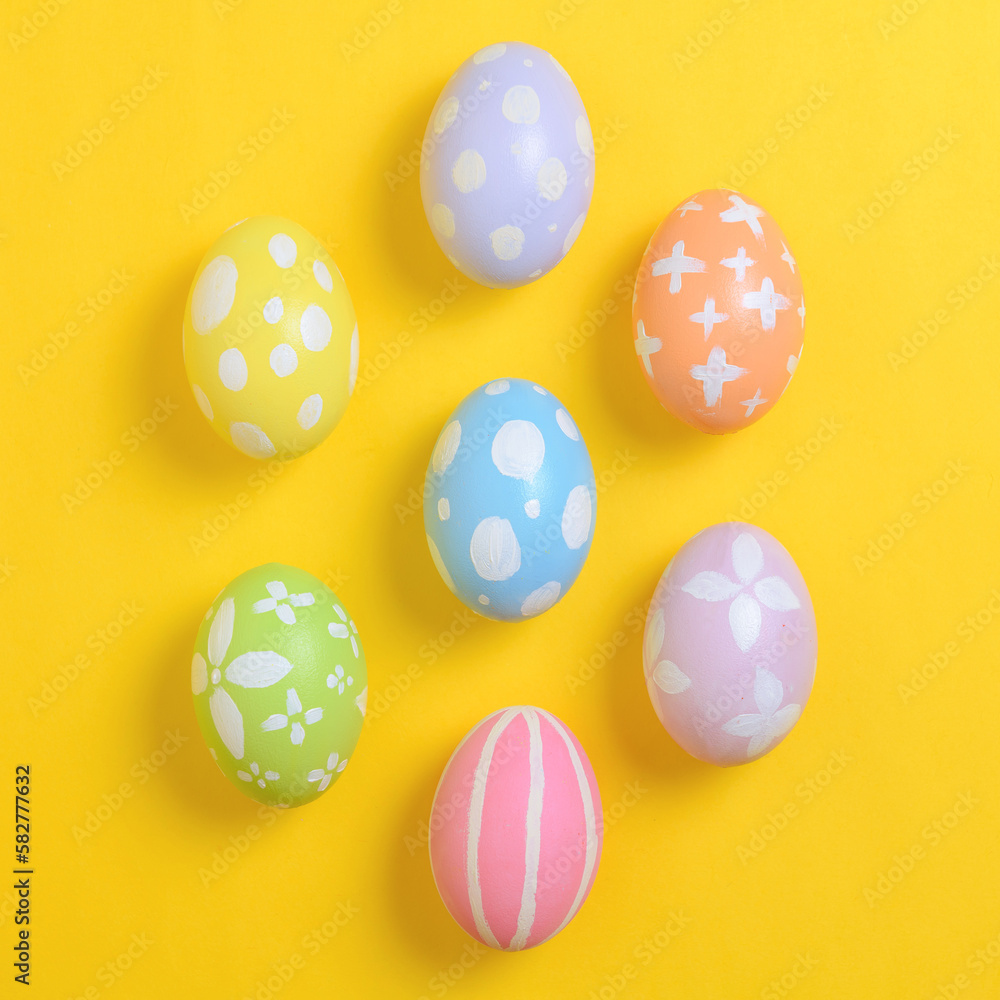 Happy easter holiday celebration concept. Group of painted colourful eggs decoration on a yellow background. Seasonal religion tradition design. Top view, flat lay, copy space.