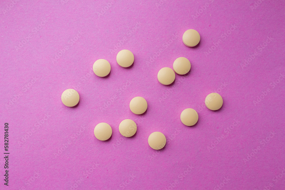 Yellow pills isolated on a pink background. Top view, flat lay. Yellow pills isolated on a pink background. Top view, flat lay.