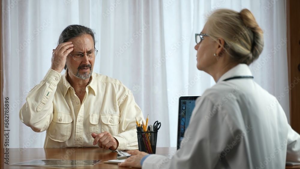Mature male patient discuss healthcare issues with woman doctor sitting across table. Concept of doctor patient relationship in office. Mature male patient discuss healthcare issues with woman doctor sitting across table. Concept of doctor patient relationship in office.