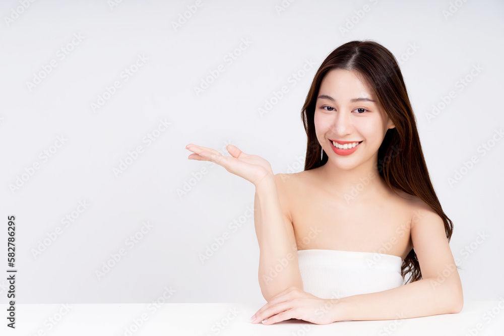 Closeup portrait of a face of young Asian girl with a healthy facial skin. Beautiful woman presenting an empty space on palm of her hand - used to promote and advertise products in studio background Closeup portrait of a face of young Asian girl with a healthy facial skin. Beautiful woman presenting an empty space on palm of her hand - used to promote and advertise products in studio background