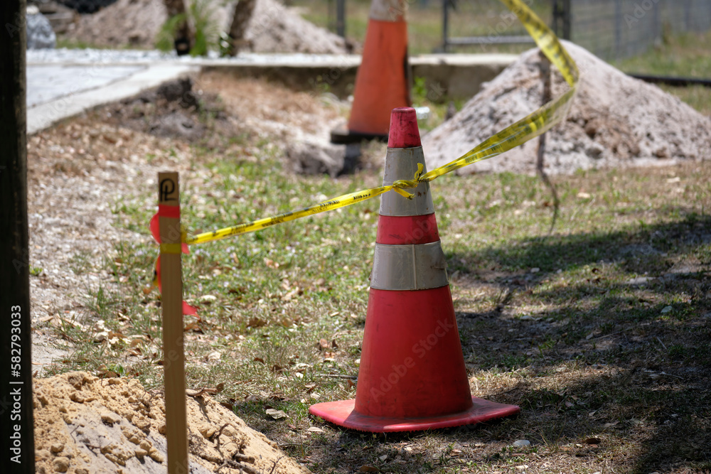 Yellow warning cones and tape as protective restriction barrier at industrial construction site. Safety for pedestrians