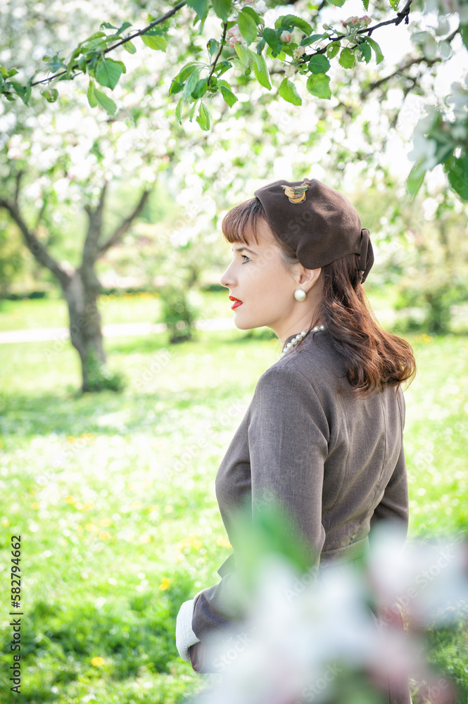 Beautiful woman retro style in gray dress stand in the spring garden Beautiful woman retro style in gray dress stand in the spring garden