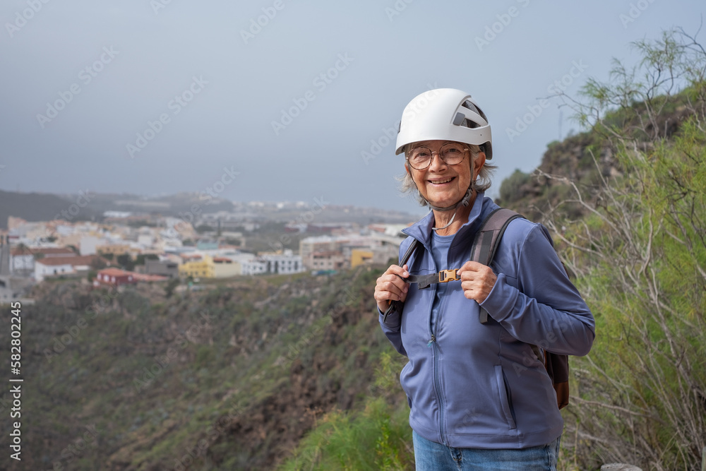Senior hiker woman with backpack and helmet enjoying trekking day on mountain - Active tourist enjoying holidays and healthy lifestyle - Freedom sport concept