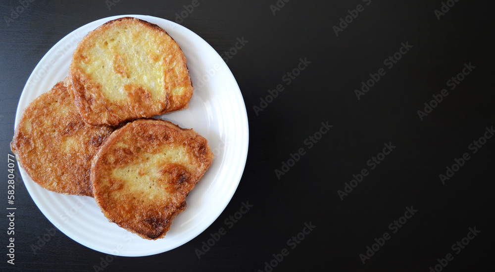 photo a white plate with croutons on a dark wooden background, a breakfast dish, fried bread