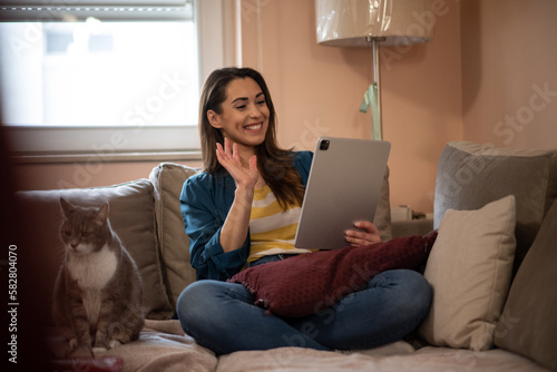 Young woman having a conference call from her home, using a tablet.