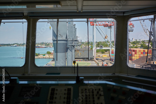 View from bulk carrier's captain's bridge to bulk cargo berth. View of port terminal from inside of captain's bridge during day